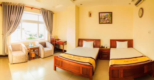 a bedroom with two beds and a chair and a window at Khách sạn cẩm lai in Vinh