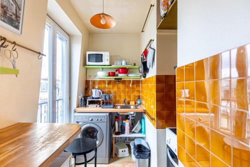 - une petite cuisine avec du carrelage jaune sur le mur dans l'établissement GuestReady - Cosy Haven near Montmartre, à Paris