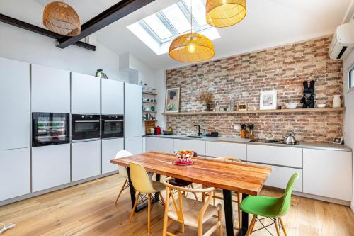 une cuisine avec des armoires blanches et une table et des chaises en bois dans l'établissement GuestReady - Bright retreat with a terrace, à Paris