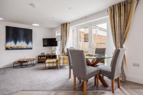 a dining room with a table and chairs and a living room at Beautiful house in Poole with parking, 2 bed & 2 bathroom in Poole