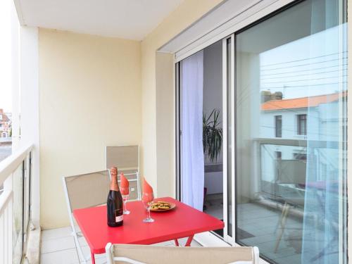 une table rouge avec une bouteille de vin sur un balcon dans l'établissement Apartment Bosquets 2 pièces balcon by Interhome, à Les Sables-dʼOlonne