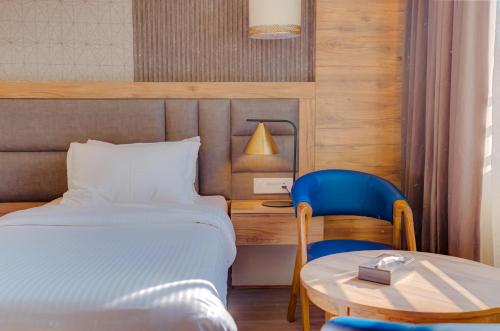 a bedroom with a bed and a table and a blue chair at Hotel Vasundhara Palace in Rishīkesh
