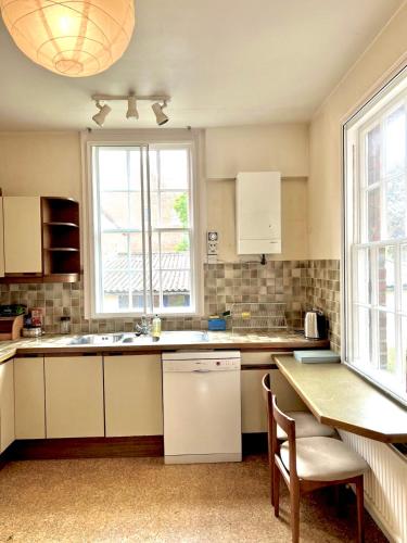 a kitchen with white cabinets and a table and windows at Historic Manor house sleeps 10, free parking in Oxford