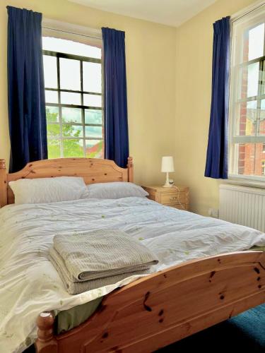 a bedroom with a large wooden bed with blue curtains at Historic Manor house sleeps 10, free parking in Oxford