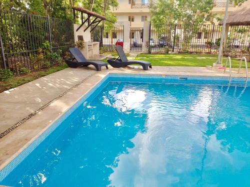 a swimming pool with two chairs in a yard at Playa Del Carmen Apartment in Playa del Carmen