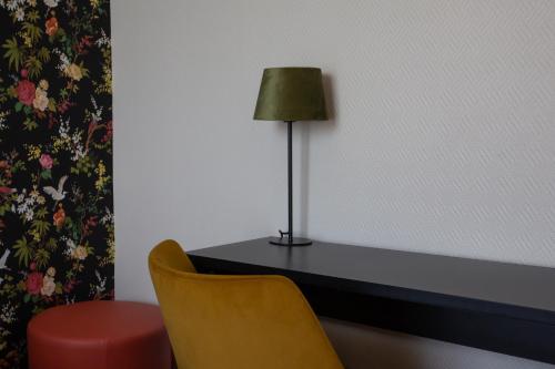 a table with a lamp and a yellow chair at Brit Hotel Europ Bergerac in Bergerac