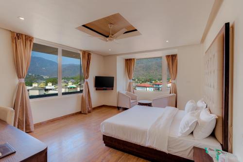 a hotel room with a bed and a large window at Hotel Vasundhara Palace in Rishīkesh