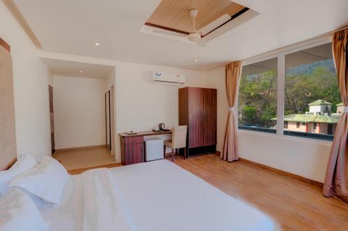 a bedroom with a bed and a desk and a window at Hotel Vasundhara Palace in Rishīkesh
