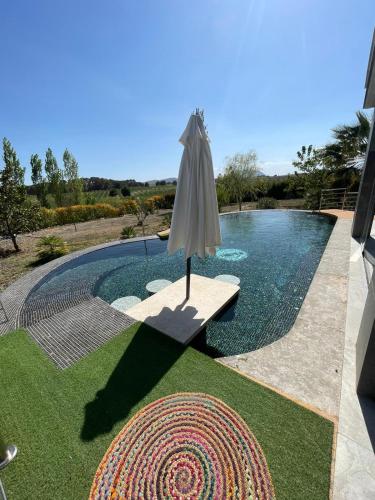 a umbrella sitting on a bench next to a swimming pool at Casa Rural Villa Cruz in Caravaca de la Cruz