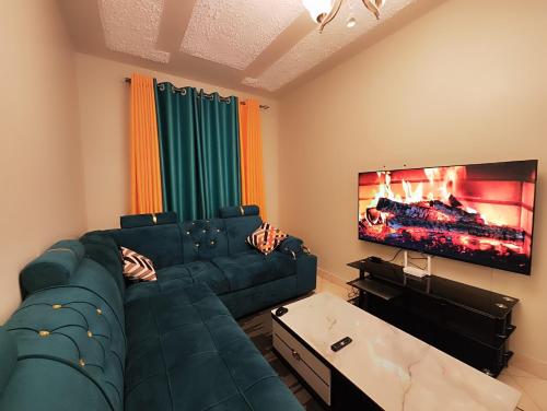 Romantic 1Bedroom Gateway in Kinoo في Kikuyu: غرفة معيشة مع أريكة وتلفزيون بشاشة مسطحة
