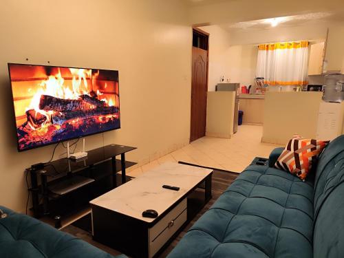 a living room with a blue couch and a fireplace at Romantic 1Bedroom Gateway in Kinoo in Kikuyu