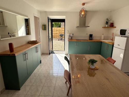 une cuisine avec des placards verts et une table en bois dans l'établissement La P'tite maison de Trého, à Tréhorenteuc