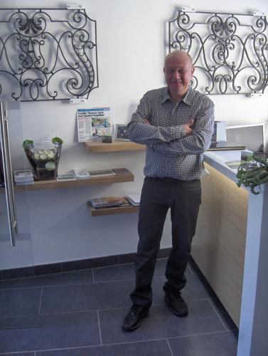 a man standing at a counter with his arms crossed at Hotel Gasthof Kapelhof in Erpe-Mere