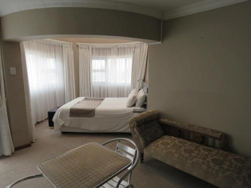 een slaapkamer met een bed, een stoel en een bank bij St Helena Bay Hotel in St Helena Bay