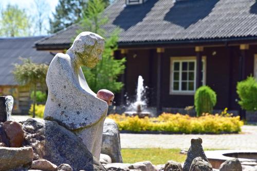 una estatua frente a una casa con una fuente en Pramogų ir konferencijų centras Paštys, en Vozgėliai