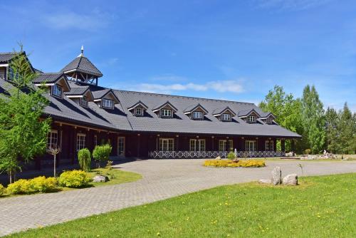 un grand bâtiment brun avec un toit en gambrel dans l'établissement Pramogų ir konferencijų centras Paštys, à Vozgėliai