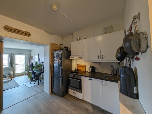 eine Küche mit weißen Schränken und einem schwarzen Kühlschrank in der Unterkunft Spacious and cozy study apartment with balcony in Oslo