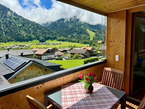 einen Tisch mit einer Blumenvase auf dem Balkon in der Unterkunft Ferienwohnung Schoppernau in Schoppernau