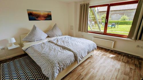 a bedroom with a bed and a large window at Happy Hero Reisen Ferienwohnungen auf Usedom nahe Achterwasser in Krummin