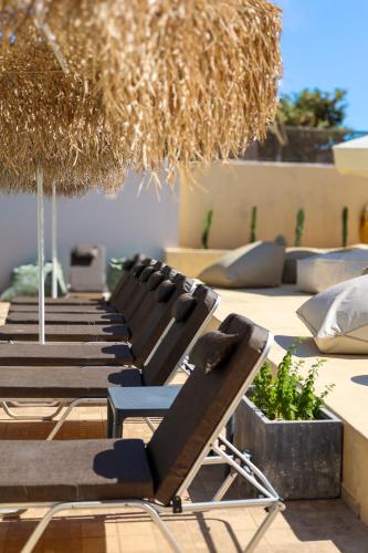 a group of lounge chairs and an umbrella at Sunshine Boutique Hotel by Estia in Malia