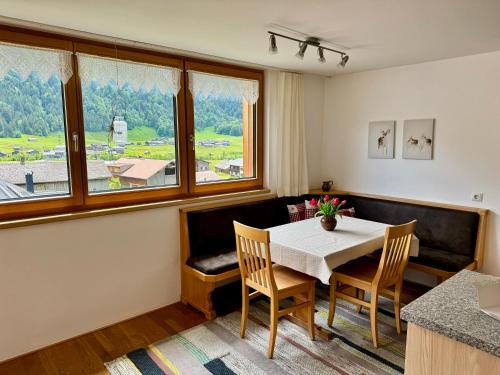 ein Esszimmer mit einem Tisch, Stühlen und Fenstern in der Unterkunft Ferienwohnung Schoppernau in Schoppernau