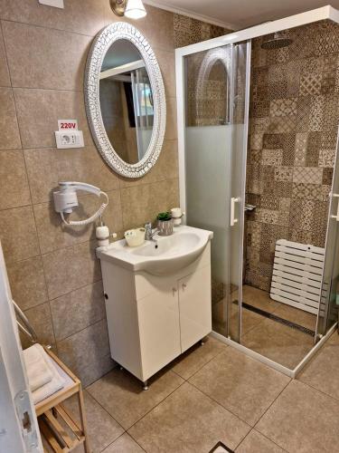 a bathroom with a sink and a shower with a mirror at Chalet Tinelu Brașov Săcele in Săcele