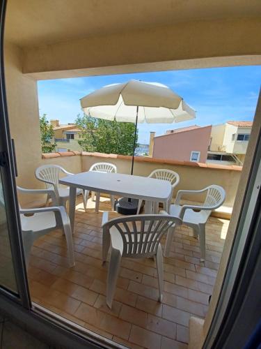 un patio avec une table, des chaises et un parasol dans l'établissement Élégant 30 M2 dans résidence 4 étoiles, au Cap d'Agde