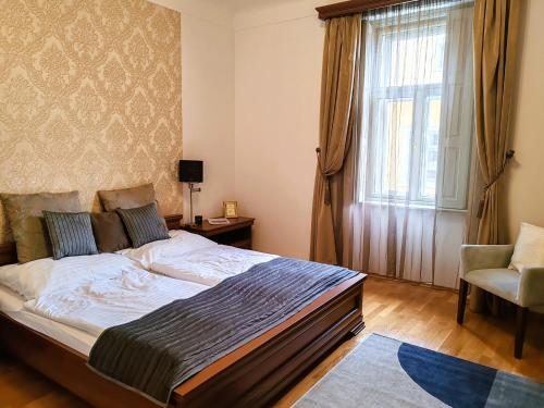 a bedroom with a bed and a window and a chair at Városi Vendégház Szentendre in Szentendre