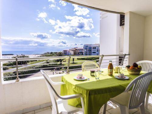d'une table et de chaises vertes sur un balcon avec vue. dans l'établissement Apartment Les Roches Marines-3 by Interhome, au Cap d'Agde