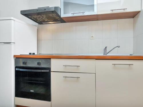 a kitchen with white cabinets and a black oven at Apartment Rubin-8 by Interhome in Zastražišće