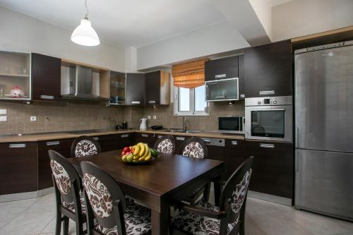 a kitchen with a wooden table with chairs and a bowl of fruit at Al Mare Apartments in Afantou
