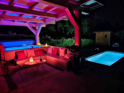 un patio avec un canapé rouge et une piscine dans l'établissement Une Oasis de détente, à Gilly-sur-Isère