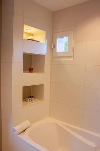 La salle de bains blanche est pourvue d'une baignoire et d'une fenêtre. dans l'établissement Une Oasis de détente, à Gilly-sur-Isère