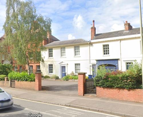a white house on the side of a street at Historic Manor house sleeps 10, free parking in Oxford