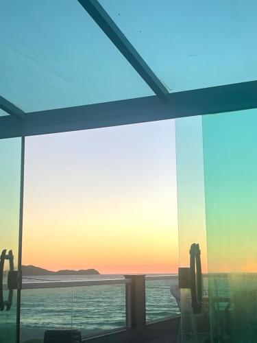 a view of the ocean from a room with glass windows at Cobertura a 5mts da Praia, Churrasqueira, Varandão, Ar condicionado in Cabo Frio