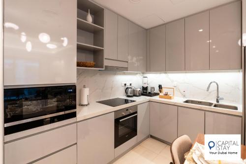 a kitchen with white cabinets and a sink at Capital Stay- Private Two Bed Apartment - The Address Beach Resort Residences Fujairah in Fujairah