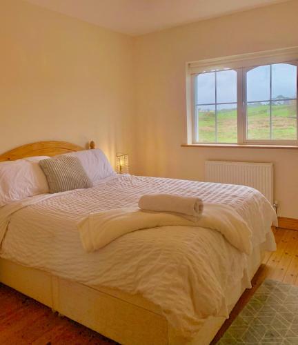 a bedroom with a large white bed with a window at Sunset view Homestay in Milltown Malbay