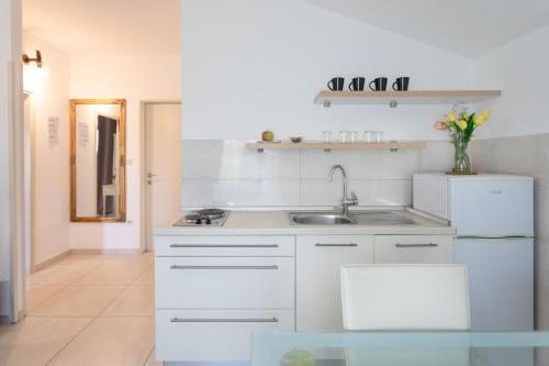 a kitchen with white cabinets and a sink at Poolside Stone Residences - Marina Bok in Novalja