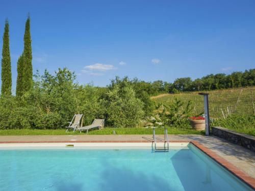 a swimming pool in a yard with two chairs at Apartment Noemi by Interhome in Podere Panzano
