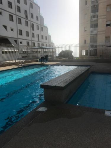 una piscina con un banco junto a un edificio en Royal Aparatment on the Sea , Blvd Nitza 34 en Netanya