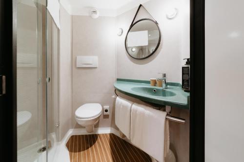 ein Badezimmer mit einem WC, einem Waschbecken und einem Spiegel in der Unterkunft ibis Namur Centre in Namur