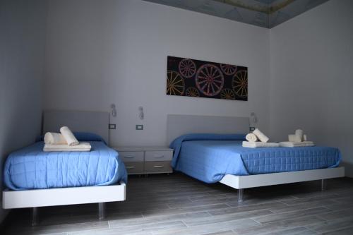 two beds in a bedroom with blue sheets at Il sogno dei mori in Ragusa