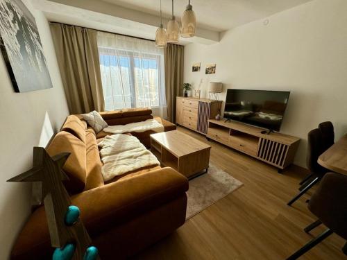 a living room with a couch and a flat screen tv at Domček pod lesom in Vysoké Tatry