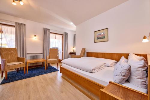 Habitación de hotel con cama y silla en Hotel Antonia en Oberammergau