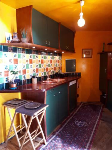 une cuisine avec des placards verts, une table et un tabouret dans l'établissement Loft atypique hyper centre à 5mn à pied de la plage de l'Écluse 2 à 4 personnes, à Dinard