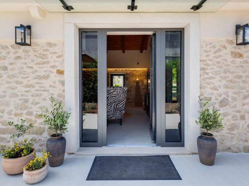 a glass door of a house with two potted plants at Holiday Home Stanca by Interhome in Donji Zemunik