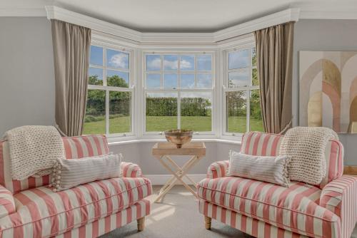 two chairs and a table in a room with windows at Port Hill House in Medbourne