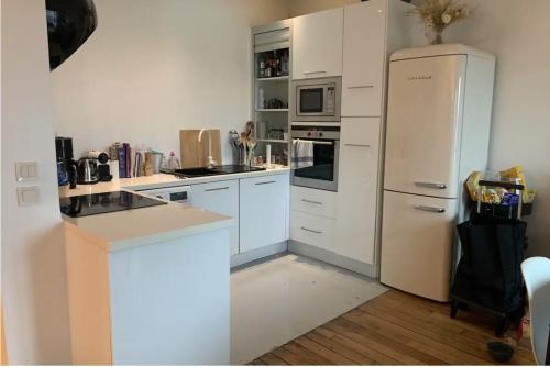  La cuisine est équipée de placards blancs et d'un réfrigérateur. dans l'établissement Cosy 10 min Paris, 30 min Disneyland, à Vincennes