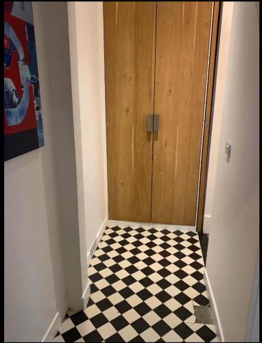 un couloir avec une porte et un sol en damier dans l'établissement Cosy 10 min Paris, 30 min Disneyland, à Vincennes