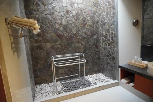 a bathroom with a shower with a stone wall at Watu Dodol Hotel & Restaurant in Banyuwangi